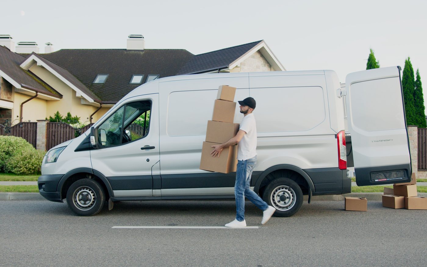 Mensajero llevando cajas desde la camioneta de reparto hasta la casa del cliente